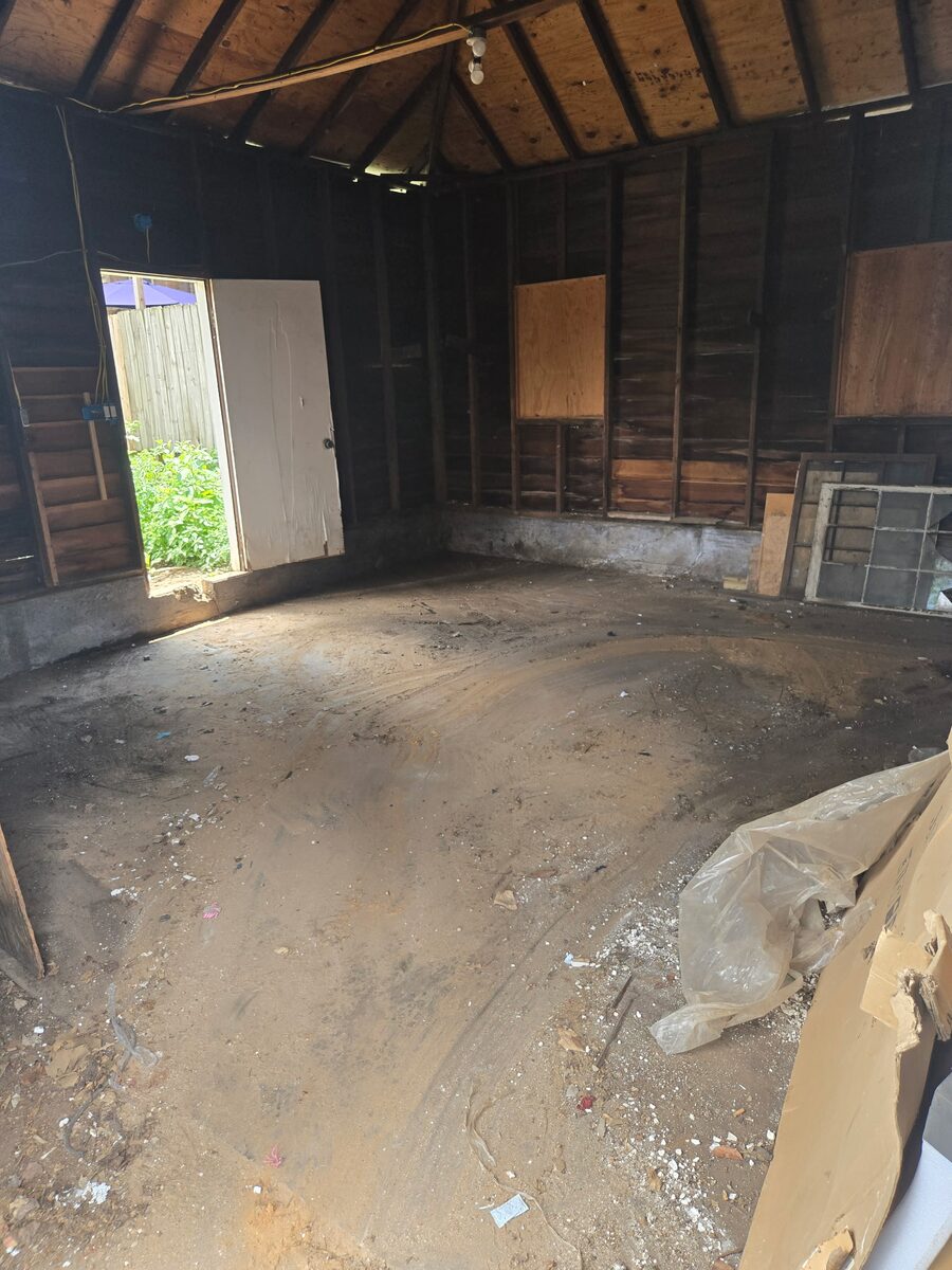 The same barn cleared to an open dirt floor, with light coming through the doorway.