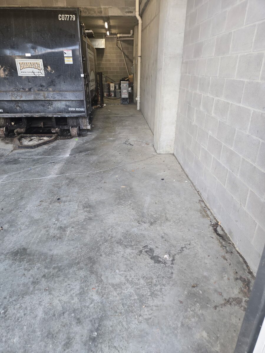 The same dumpster bay cleared to bare concrete, with only the dumpster left at the far end.