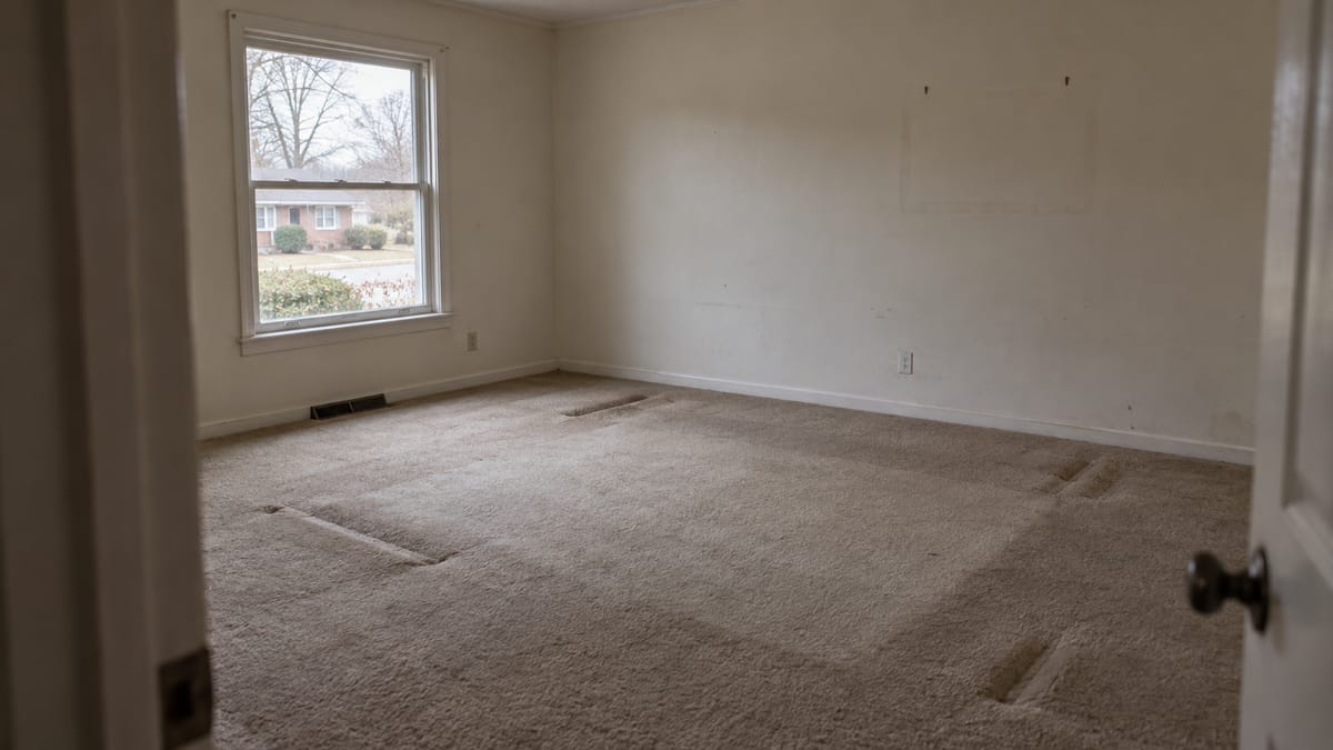 An empty spare bedroom with bare carpet and a window, ready for guests.
